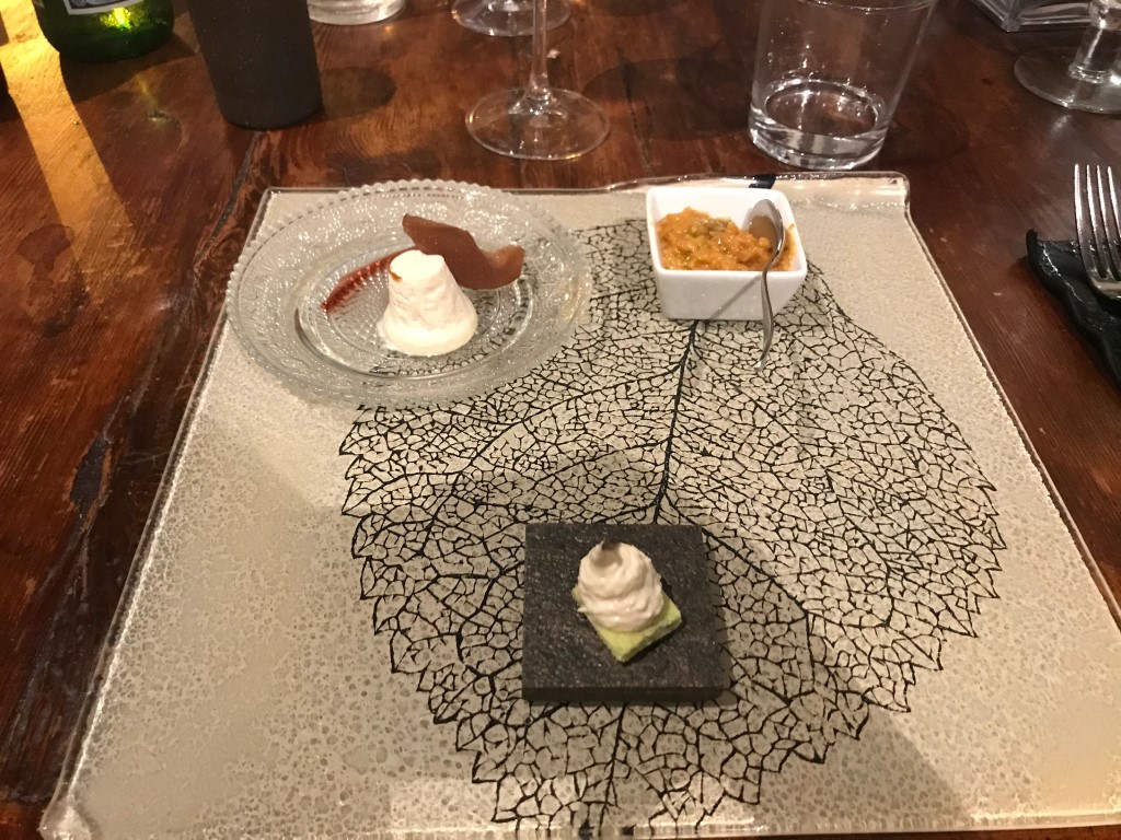 Elegant multi-course appetizer presentation at Osteria I'Ciocio, Suvereto, on a leaf-etched glass board