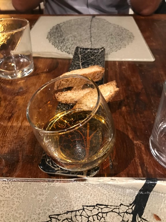 Digestivo glass and toasted bread bites on leaf-patterned tableware at Osteria I'Ciocio, Suvereto