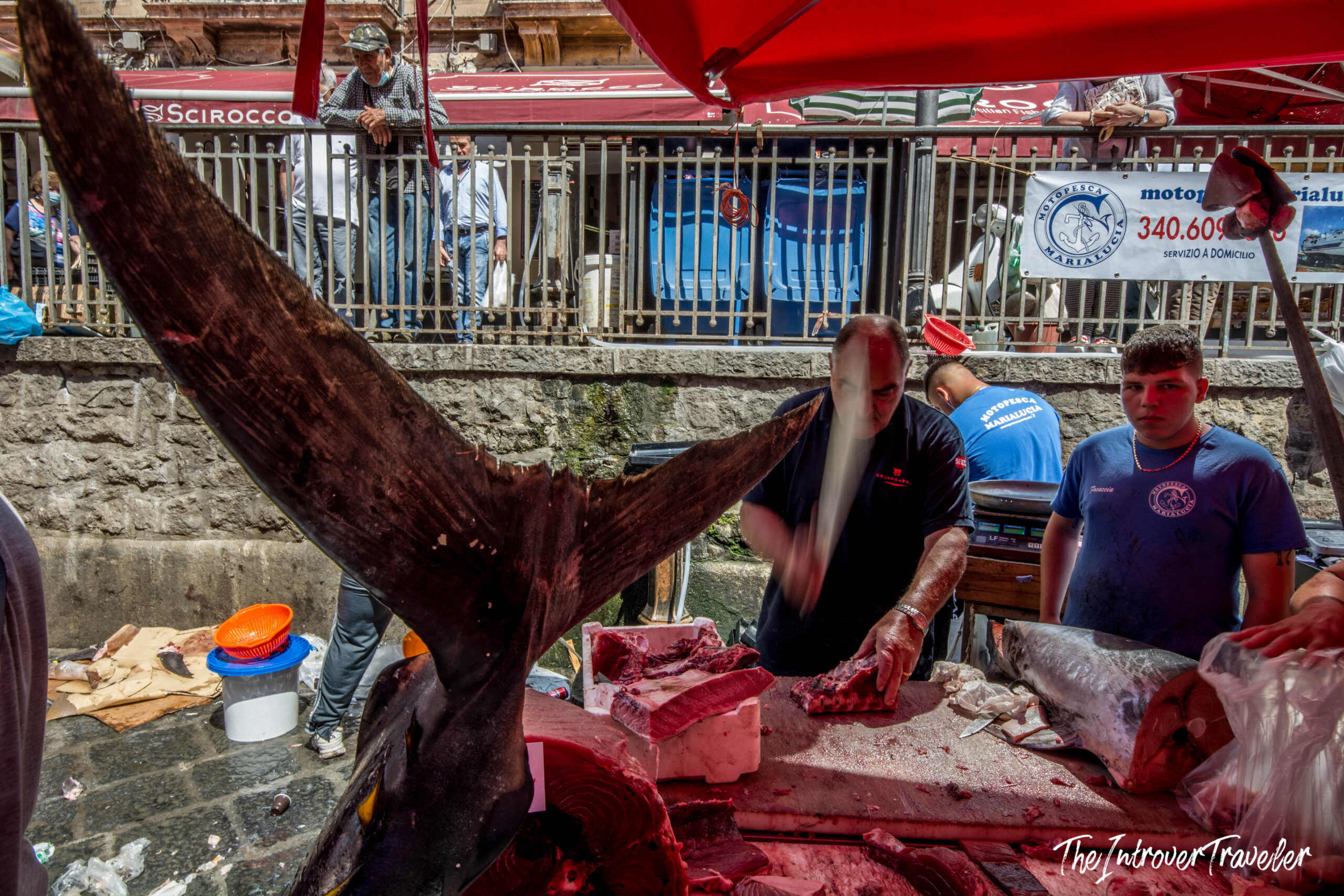 Vendor butchering a whole bluefin tuna at Catania fish market, Sicily, tail fin raised high