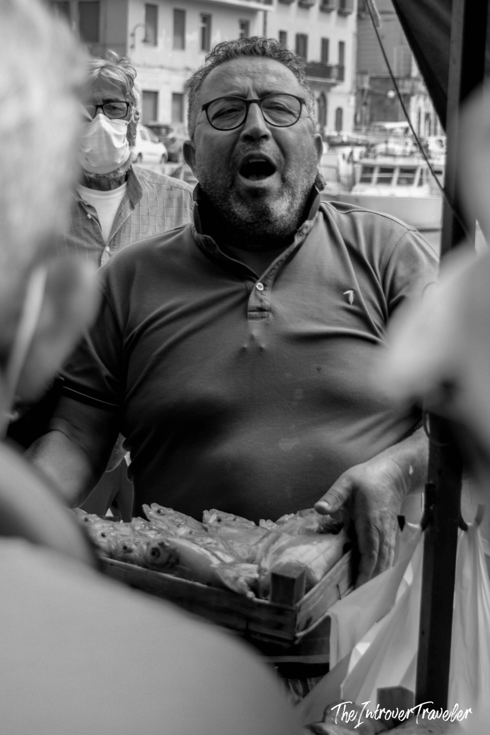 Animated fish market vendor calling out prices, holding a tray of fresh catch at a coastal city market