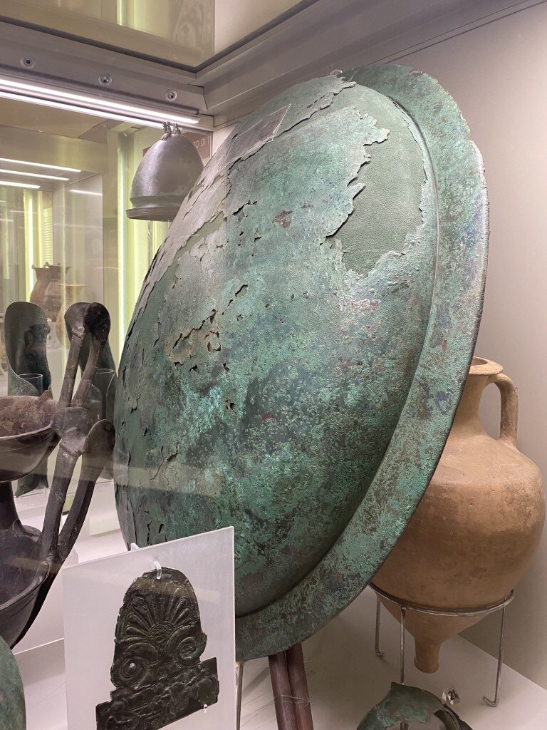 Ancient Etruscan bronze shield with green patina on display at Villa Giulia, Rome