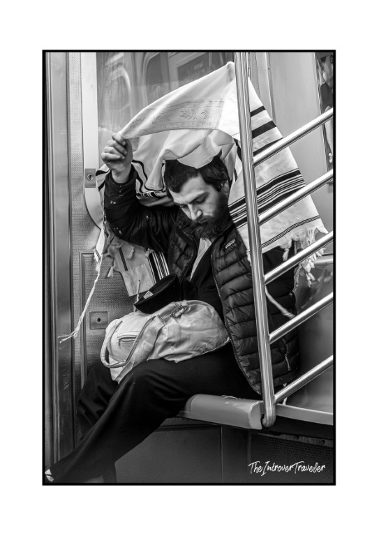 Jewish man draped in a tallit praying on the New York City subway, capturing everyday NYC life