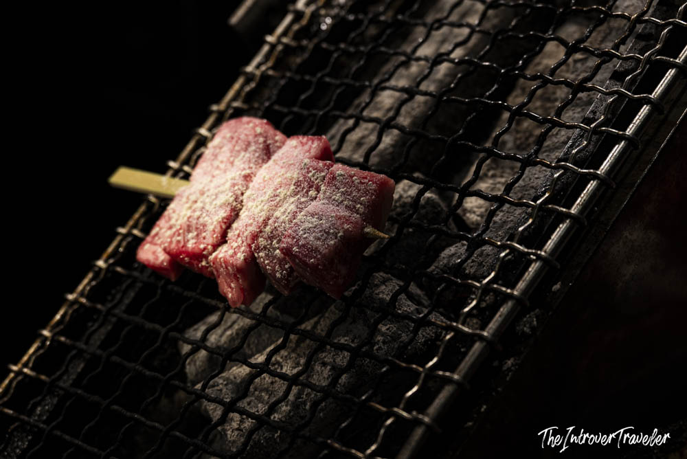 Seasoned wagyu beef skewers grilling over charcoal at Nishiki Market, Kyoto