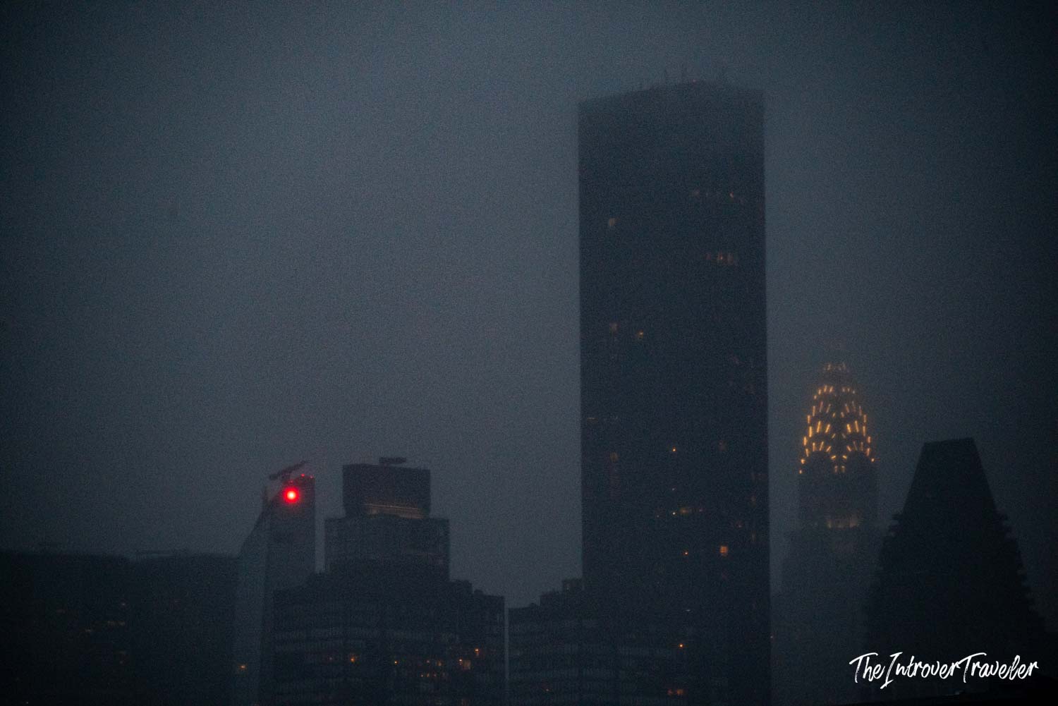 Chrysler Building Art Deco crown glowing through foggy Manhattan night skyline
