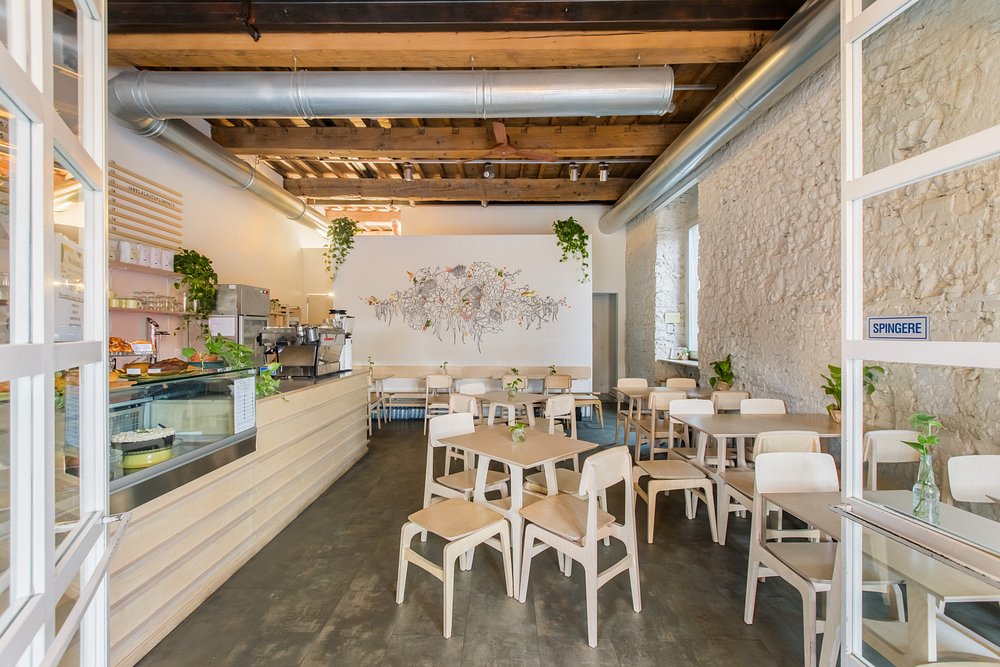 Bright interior of Melaleuca Bistrot in Florence, with light wood furniture, stone walls, and floral wall art