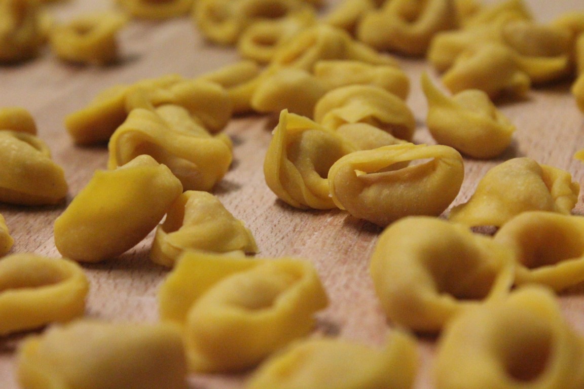 Fresh handmade tortellini laid out on a wooden board, the iconic stuffed pasta of Bologna