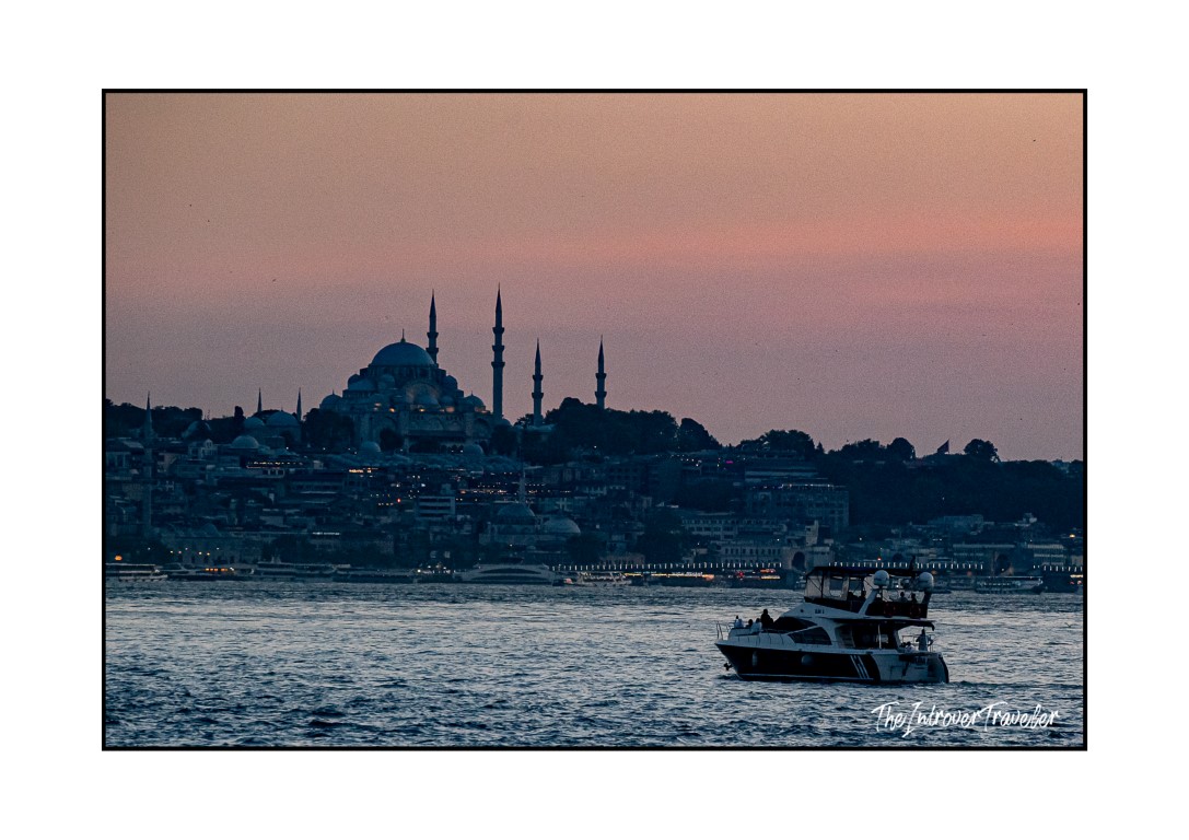 Suleymaniye Mosque silhouette at dusk over the Bosphorus, with a boat in the foreground