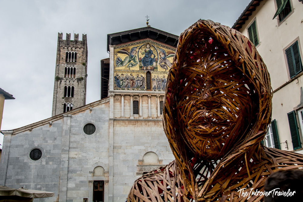 Woven wood sculpture in Piazza San Frediano, Lucca, with the basilica's Byzantine mosaic facade behind