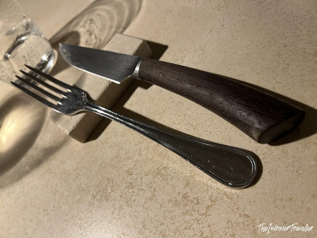 Fork and steak knife with dark wood handle set on a stone table at Trattoria Da Lucio, Rimini
