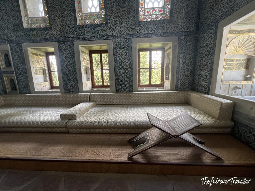 Topkapi Palace Harem interior with Iznik-tiled walls, cushioned divans, and a carved Quran stand