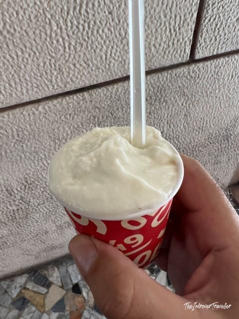 Creamy white gelato in a red cup with straw, from a top-rated gelateria in Bologna