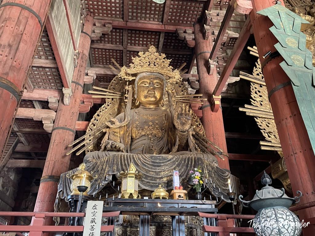 Gilt Kokuzo Bosatsu statue inside Todaiji Temple, Nara, with red wooden beams above