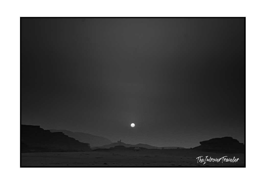 Black and white moonrise over Wadi Rum desert, Jordan, with rocky silhouettes and vast flat terrain