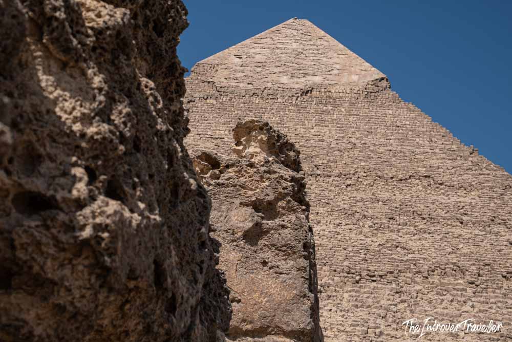 Close-up view of the Pyramid of Khafre at Giza, framed by weathered limestone rock in the foreground
