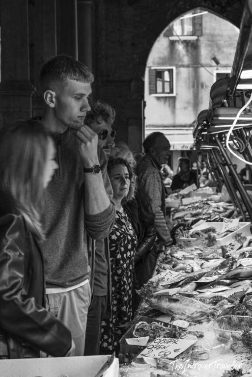 Visitors browsing fresh fish and oysters at a covered coastal city fish market stall