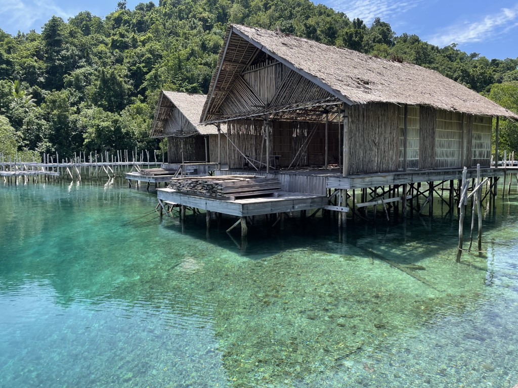 Traditional stilt huts over crystal-clear turquoise water in Raja Ampat, Indonesia