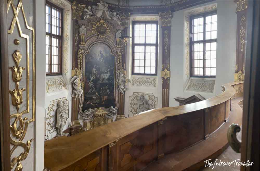 Baroque chapel interior at the Belvedere Palace Vienna, with gilded altar, painted panels, and curved wooden pews