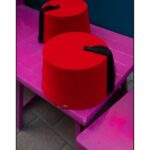 Two red fez hats with black tassels on a bright purple bench in Istanbul