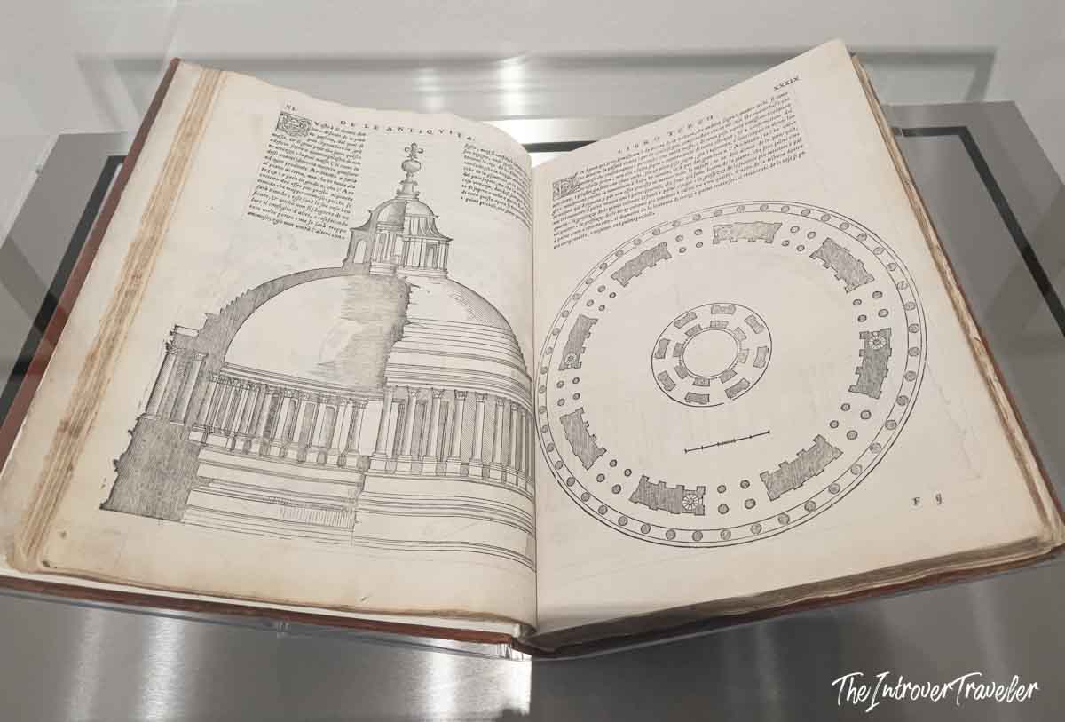 Antique architectural treatise open to Pantheon elevation and floor plan drawings, displayed in a museum case