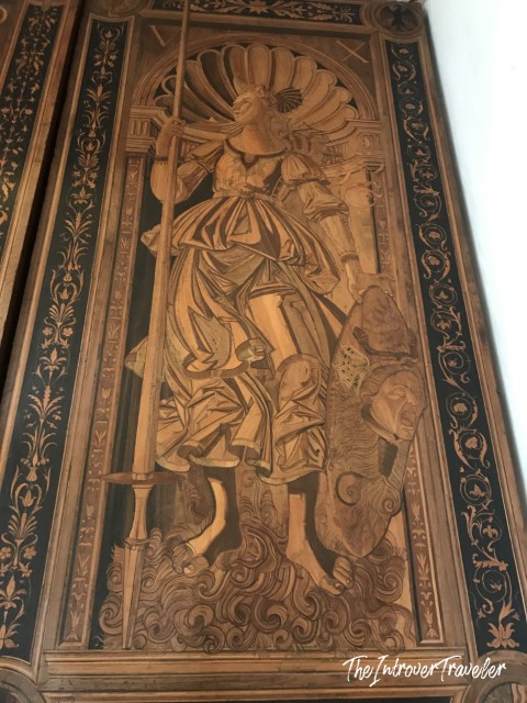 Intricate intarsia wood panel in the Studiolo of Federico da Montefeltro, Urbino, depicting a robed female figure