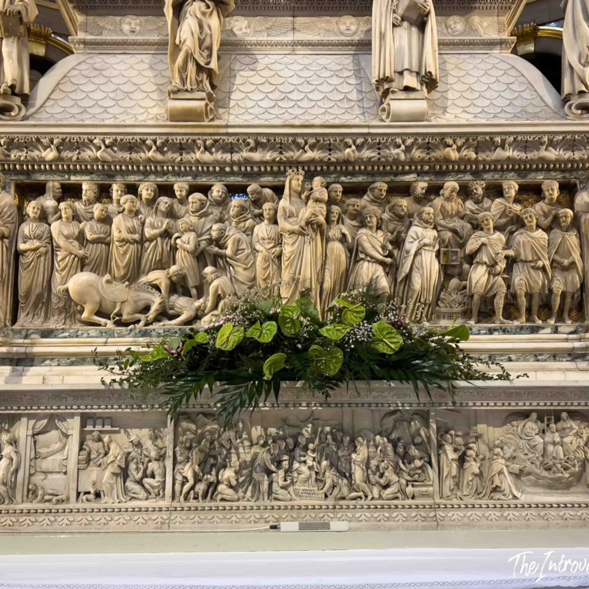 Detailed marble relief carvings on the Ark of Saint Dominic, Bologna, with a floral arrangement below