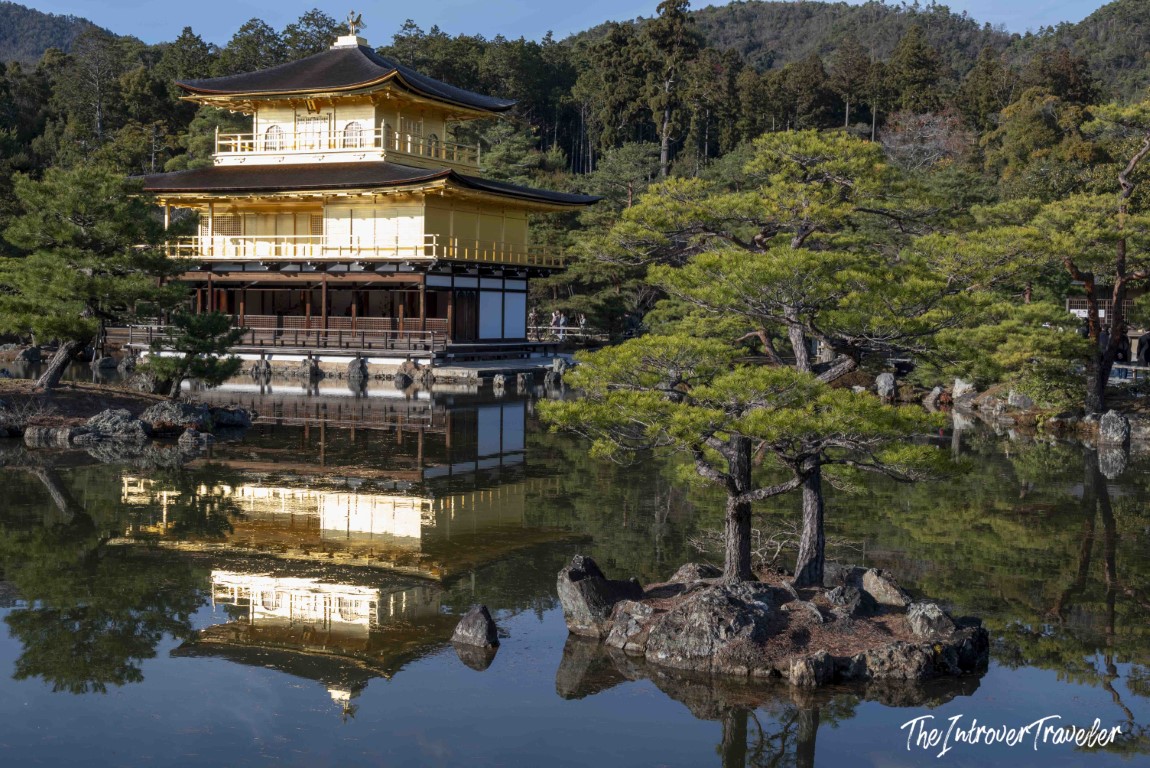 Kinkaku-ji Golden Pavilion reflected in Kyoko-chi pond, with pine trees and forested hills in Kyoto