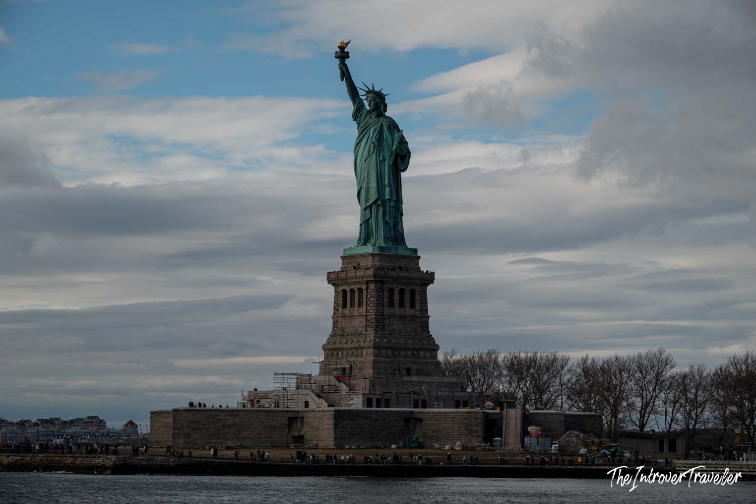 Statue of Liberty on Liberty Island viewed from the ferry, torch raised under a cloudy New York sky