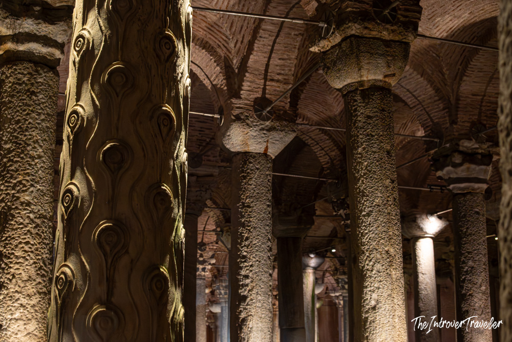 Ornately carved column with swirling reliefs inside the Basilica Cistern, Istanbul, among rows of ancient pillars