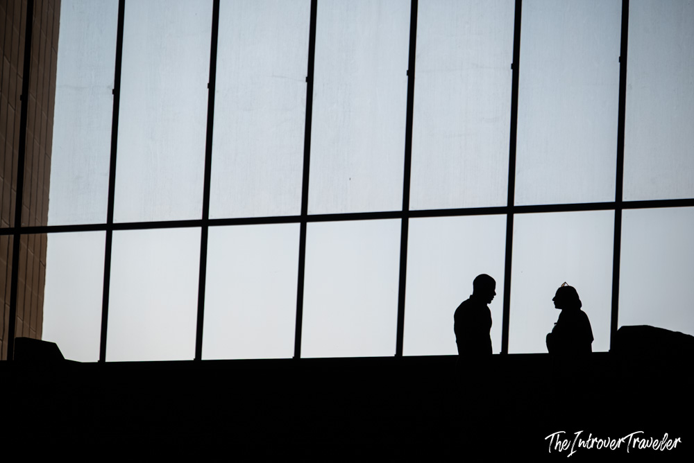 Two visitors silhouetted against the Grand Egyptian Museum's giant window overlooking the Giza pyramids