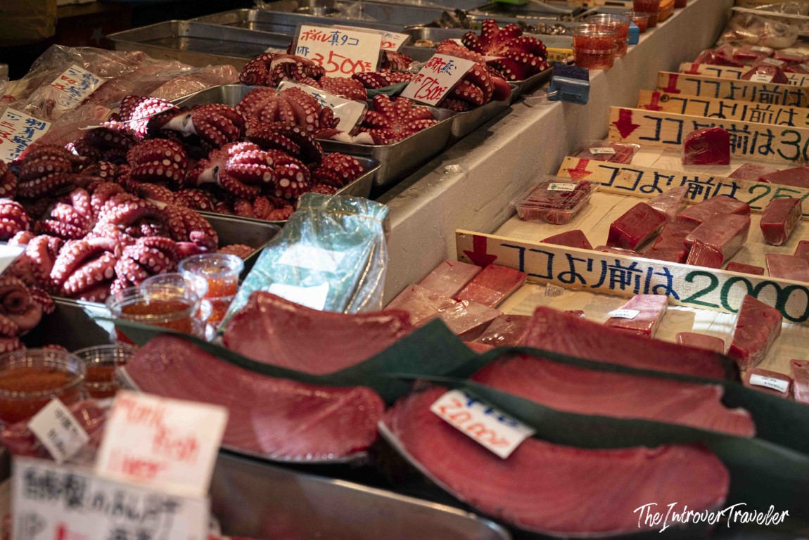 Fresh octopus and tuna slices displayed at a Tsukiji fish market stall in Tokyo, with Japanese price signs