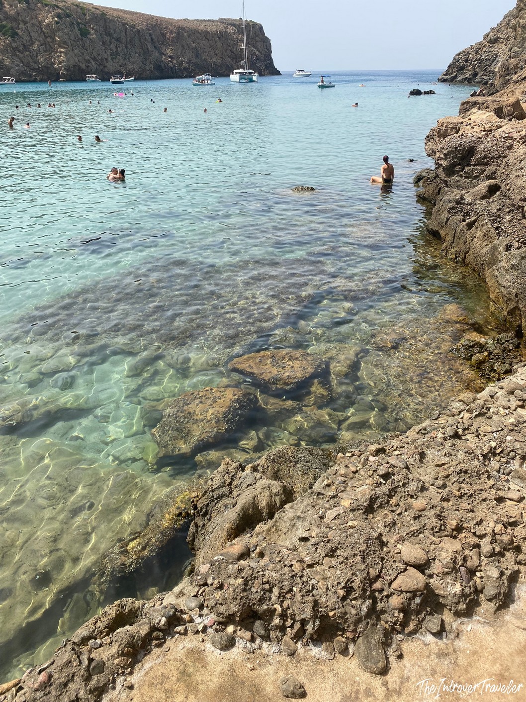 Rocky cove at Tuerredda beach, Teulada, with crystal-clear turquoise water and swimmers in South Sardinia