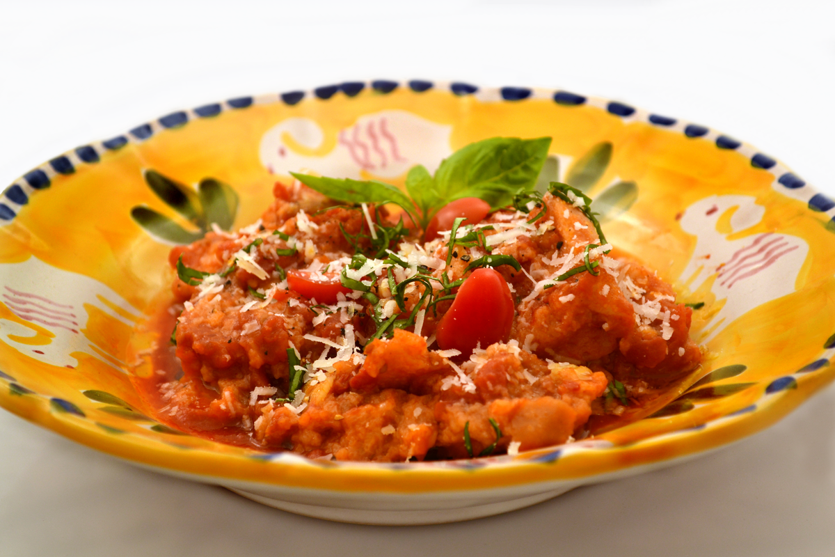 Tuscan ribollita or pappa al pomodoro served in a hand-painted Deruta ceramic bowl with basil and Parmesan