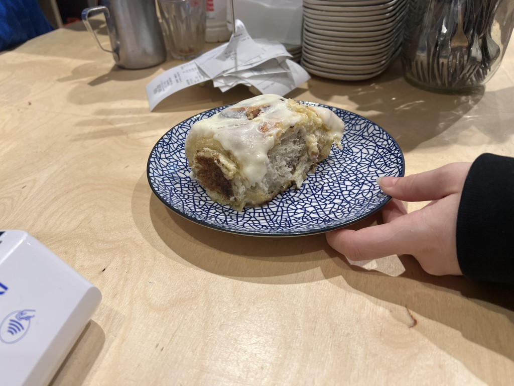 Glazed cinnamon roll on a blue patterned plate at Melaleuca Bistrot, Florence