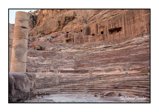 Rock-carved Nabataean Theater in Petra, Jordan, with tiered sandstone seats and tomb facades above