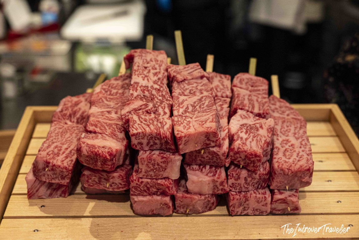 Raw Wagyu beef skewers on a wooden board at Tsukiji outer market, Tokyo