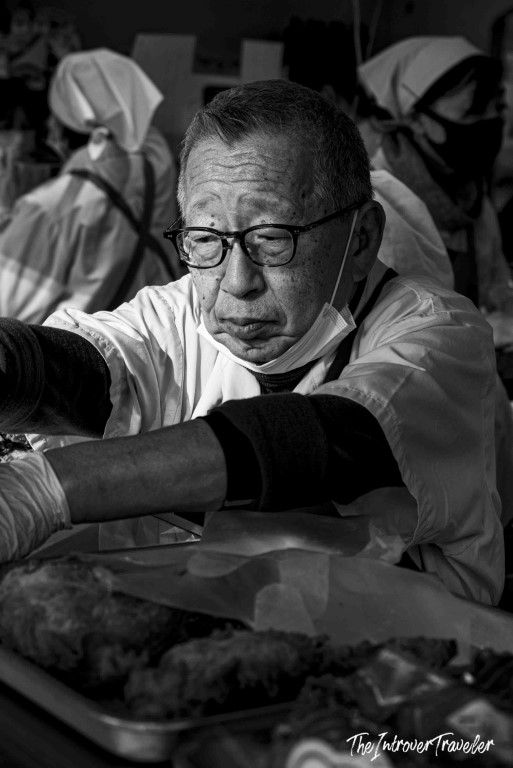 Elderly Japanese vendor preparing fresh seafood at Tsukiji fish market, Tokyo