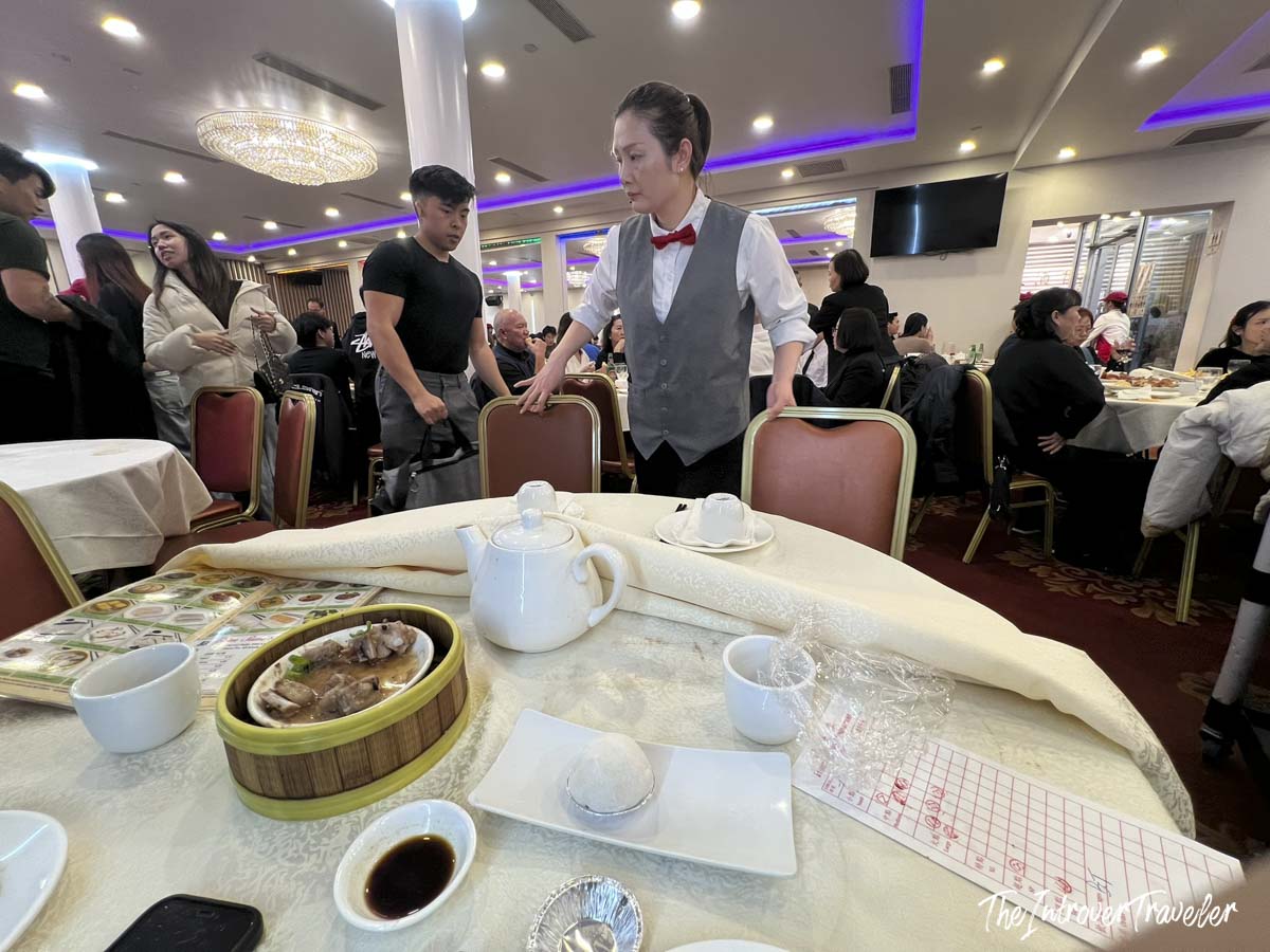 Waitress serving dim sum at House of Joy, Chinatown Manhattan, with steamed spare ribs and tea on the table