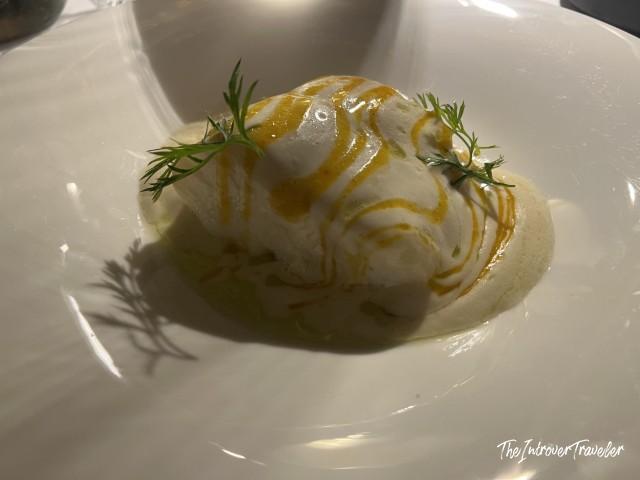 Elegant plated dish at L'Ebbrezza di Teonilla, Naples, with cream sauce, saffron drizzle, and fresh dill