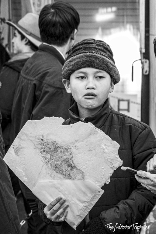 Young boy holding a fish fossil slab for sale at Tsukiji market, Tokyo