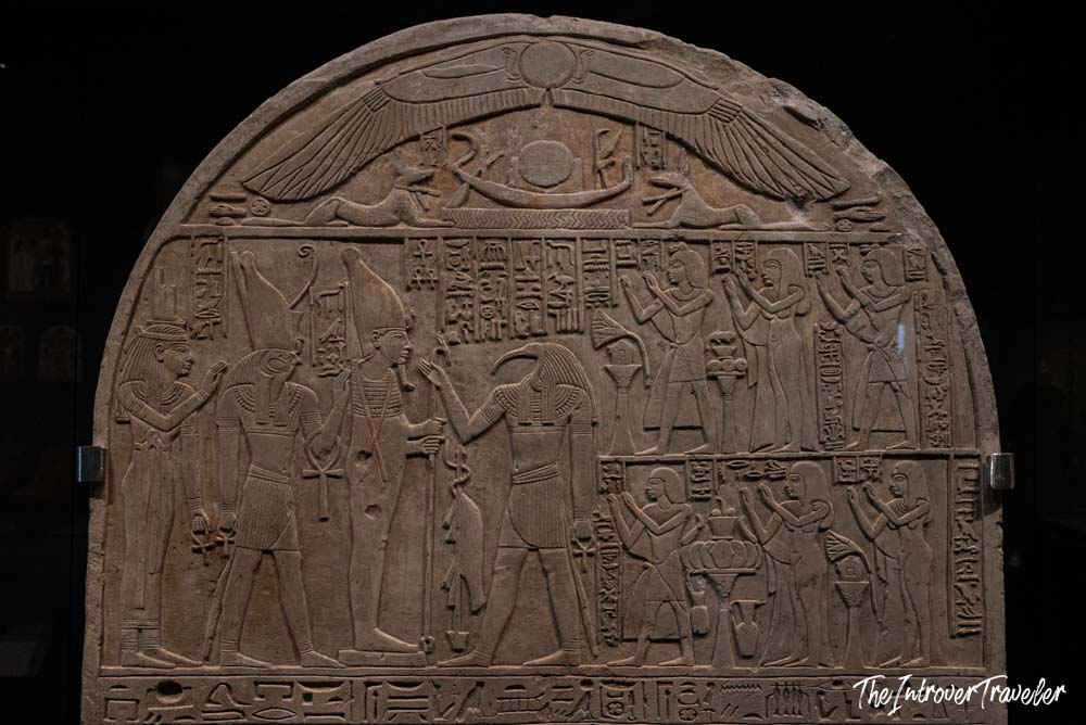Ancient Egyptian limestone stele with hieroglyphs and deity reliefs on display at the Grand Egyptian Museum, Cairo