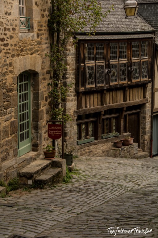 Cobblestone street in Dinan lined with medieval half-timbered buildings and a bed and breakfast sign