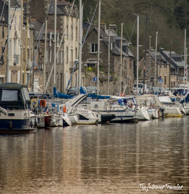 Sailboats moored at Dinan port along the Rance River, lined with traditional Breton stone buildings