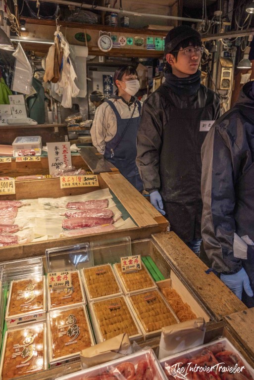 Tsukiji fish market vendor displaying fresh uni and tuna cuts with yen price tags, Tokyo