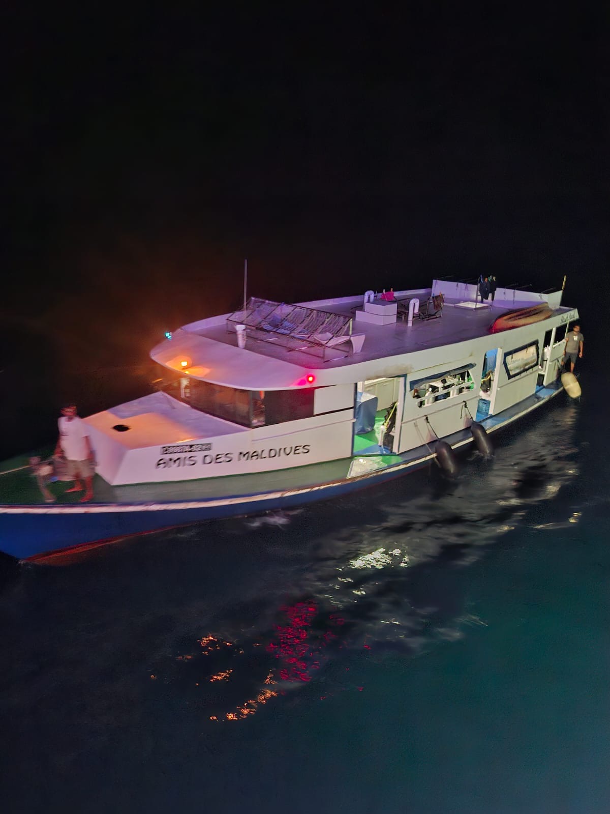 The Amis des Maldives dhoni boat lit up at night, used as dive base for Maldives liveaboard trips