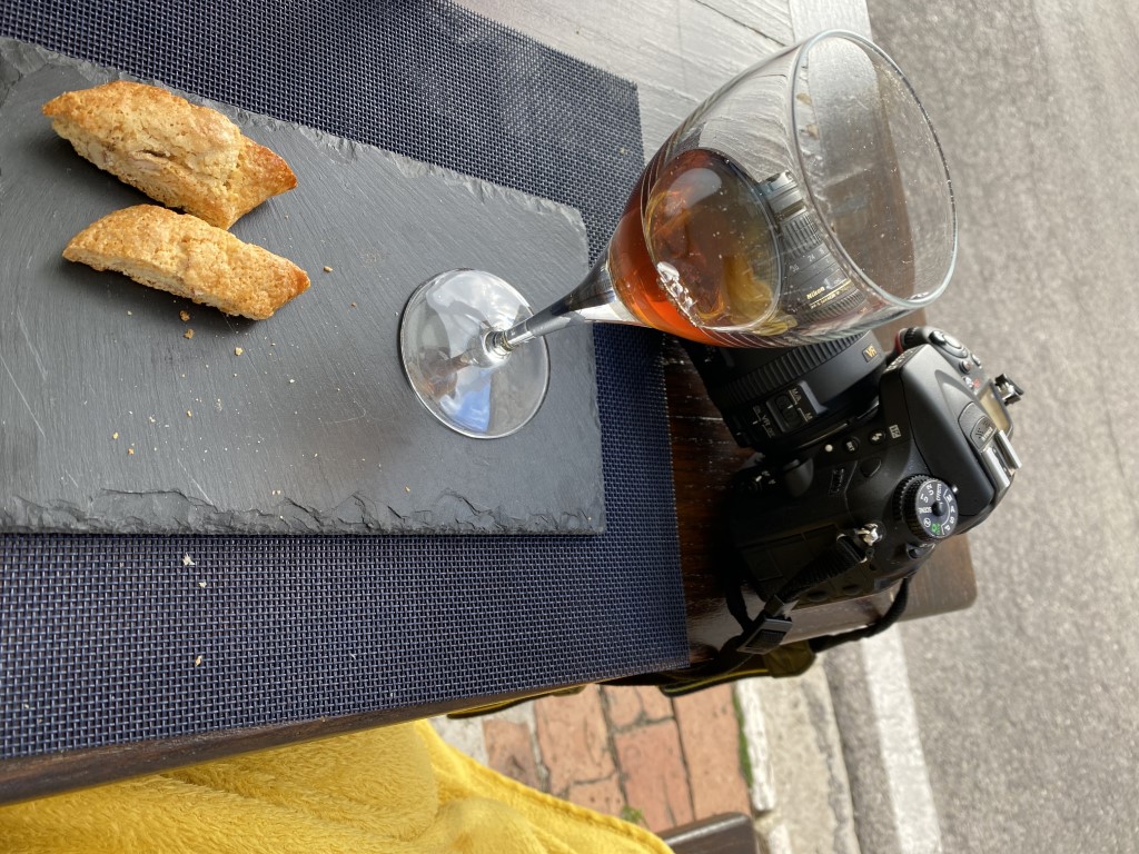 Tuscan cantucci and vin santo beside a Nikon D7100 camera at a cafe in San Giovanni d'Asso