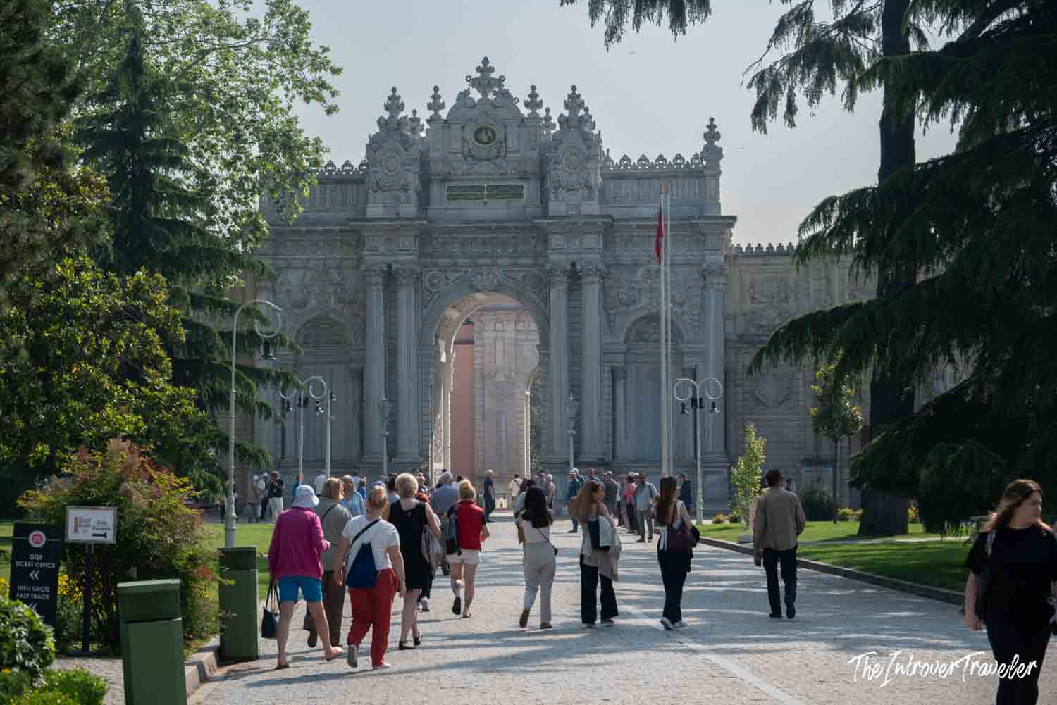 Tourists walking toward the ornate Imperial Gate of Dolmabahce Palace in Istanbul