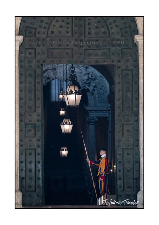 Swiss Guard in colorful uniform standing at the bronze doors entrance to St. Peter's Basilica, Vatican