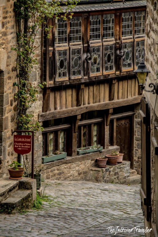 Cobblestone alley in Dinan with a half-timbered medieval building and bed and breakfast sign