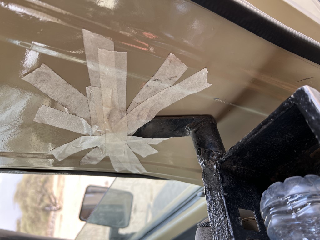 Cracked safari vehicle window repaired with tape, showing rough conditions on a Tanzania savanna trip