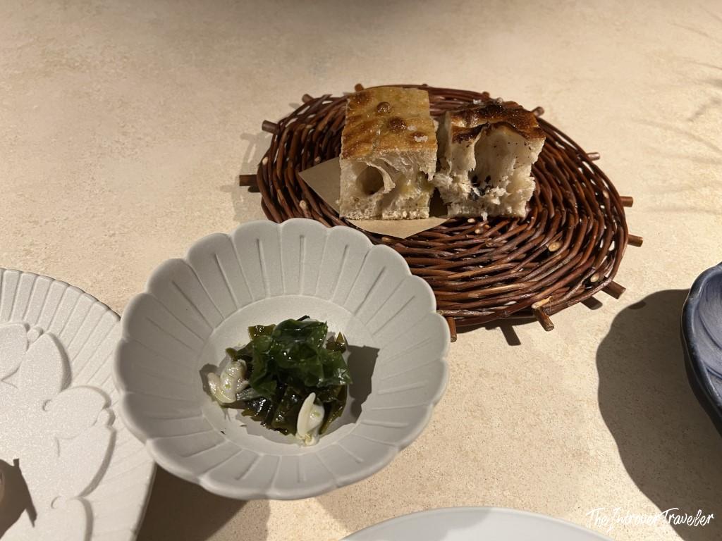 Focaccia bread on a wicker trivet with seaweed salad starter at Trattoria Da Lucio, Rimini
